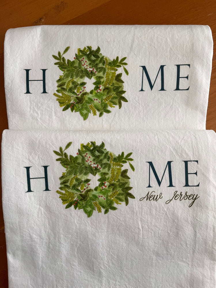 Personalized tea towels featuring "HOME New Jersey" with a decorative greenery wreath design, perfect for kitchen decor.