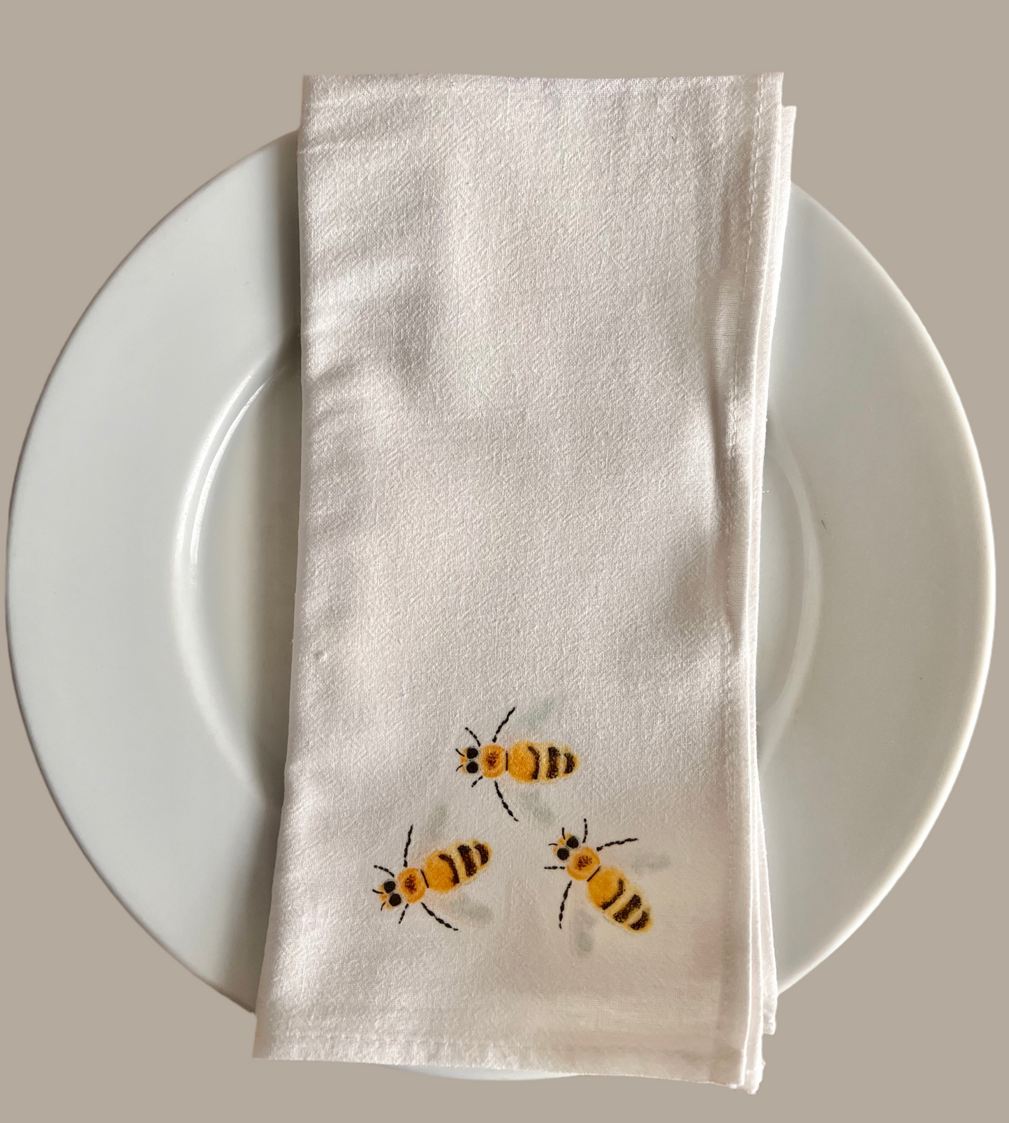White cotton napkin with illustrated bees on plate, nature-inspired table decor