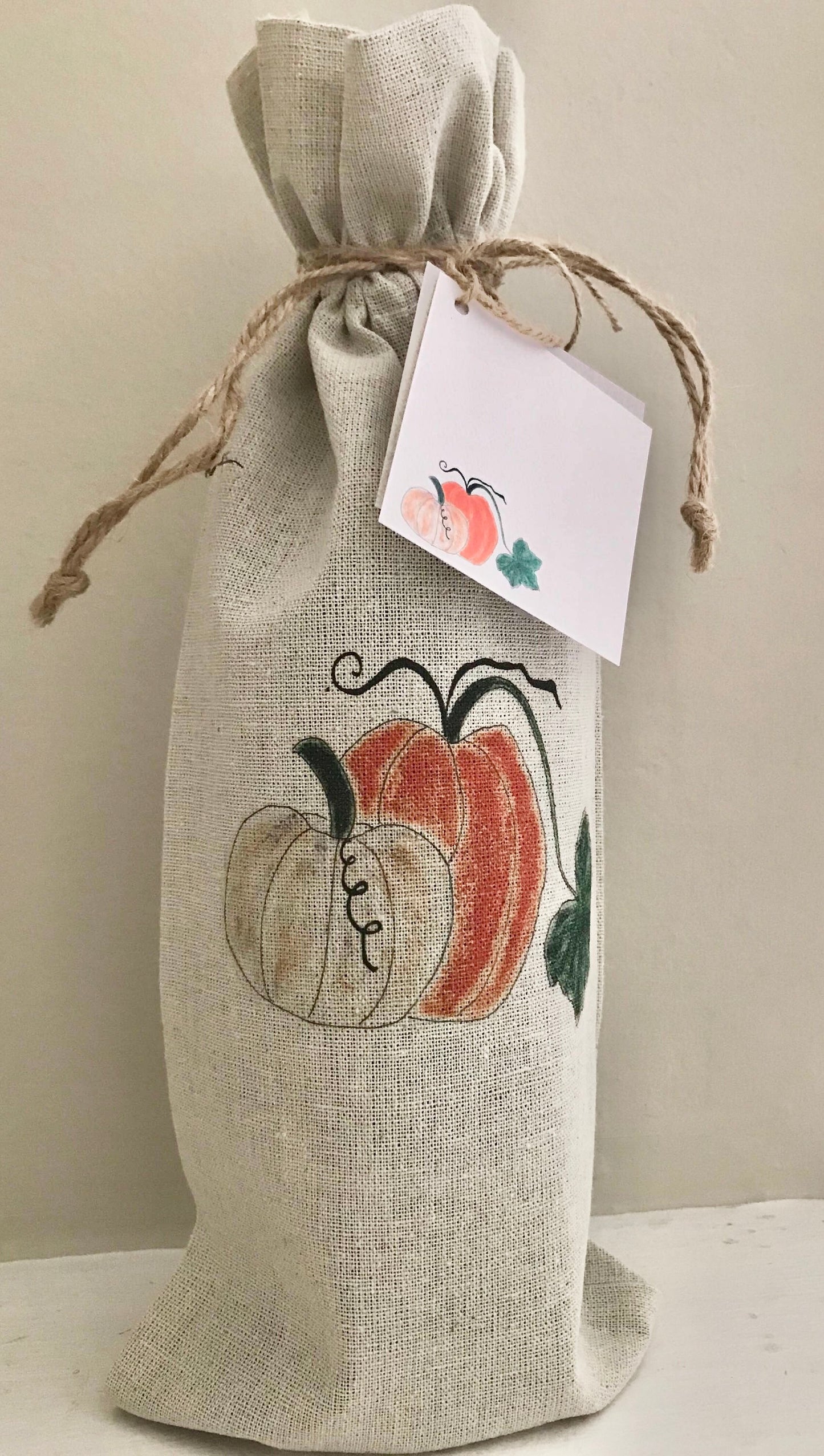 Burlap wine bag with pumpkins and a tag on a neutral background