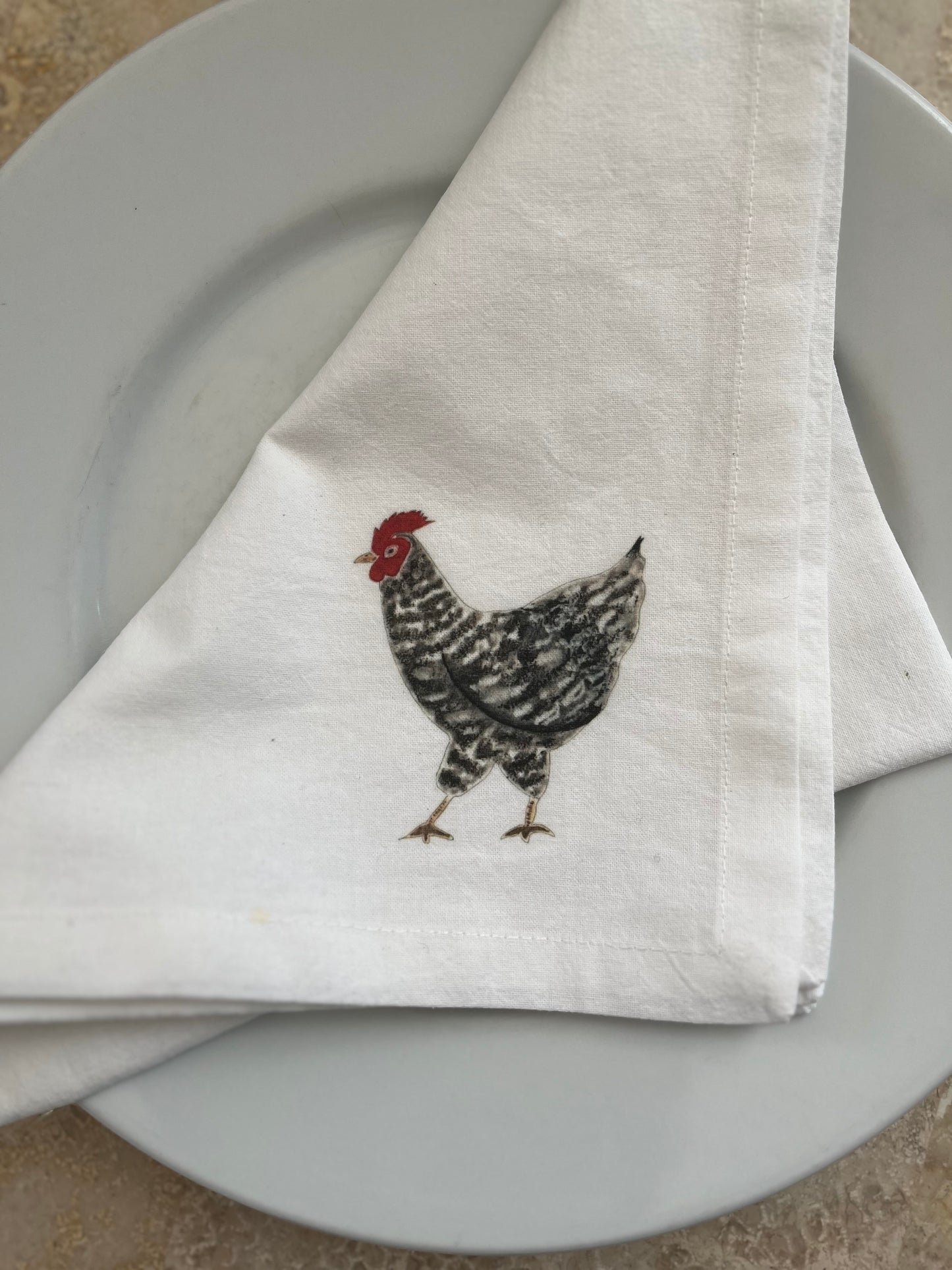 Cotton napkin with illustrated chicken design on a white dinner plate