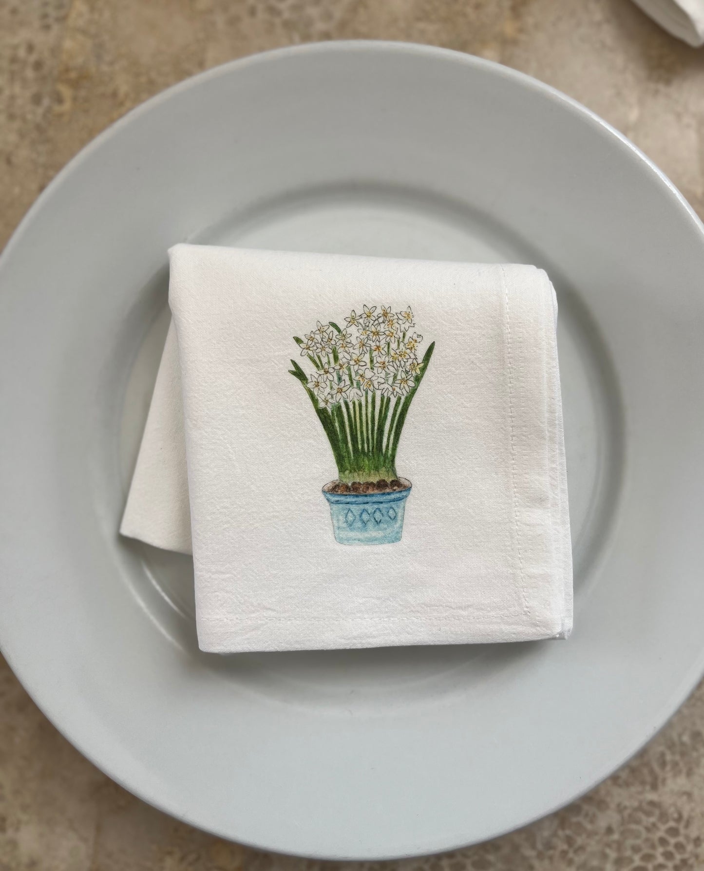 White cotton napkin with potted flower illustration on white plate