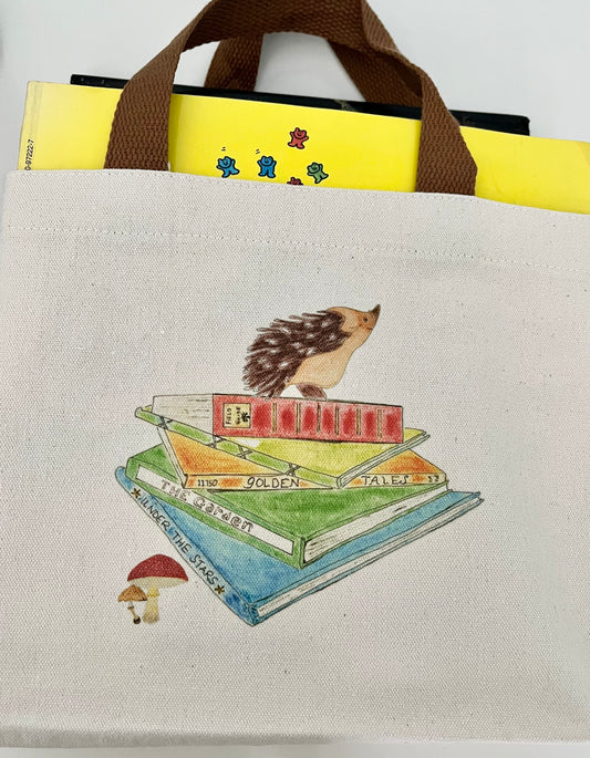 Canvas tote bag with hedgehog and books illustration, brown handle, books inside bag