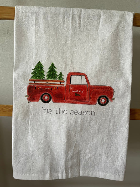 Christmas tea towel with red truck carrying trees, 'tis the season text, holiday kitchen decor