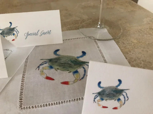 Watercolor crab place cards and cotton napkin on table, coastal entertaining decor