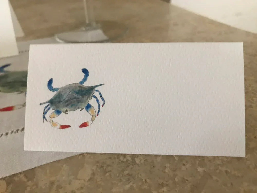 Blank tented place card with watercolor blue crab illustration on textured paper