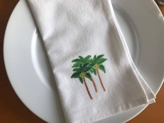 White cotton napkin with illustrated palm trees on a white plate, table setting decor