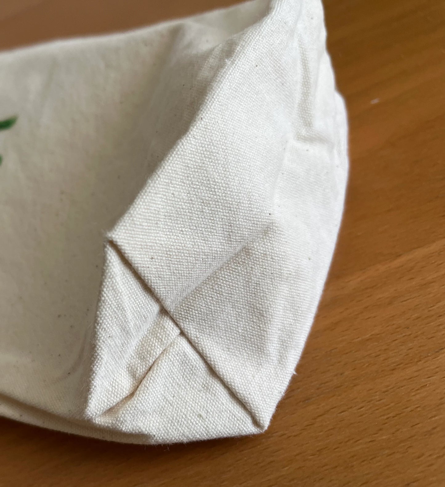 Eco-friendly cream cotton fabric bag corner on wooden surface, Happenstance Creations