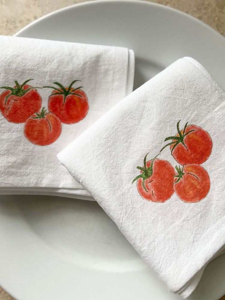 White cotton napkins with illustrated red tomatoes, perfect for nature-inspired table settings.