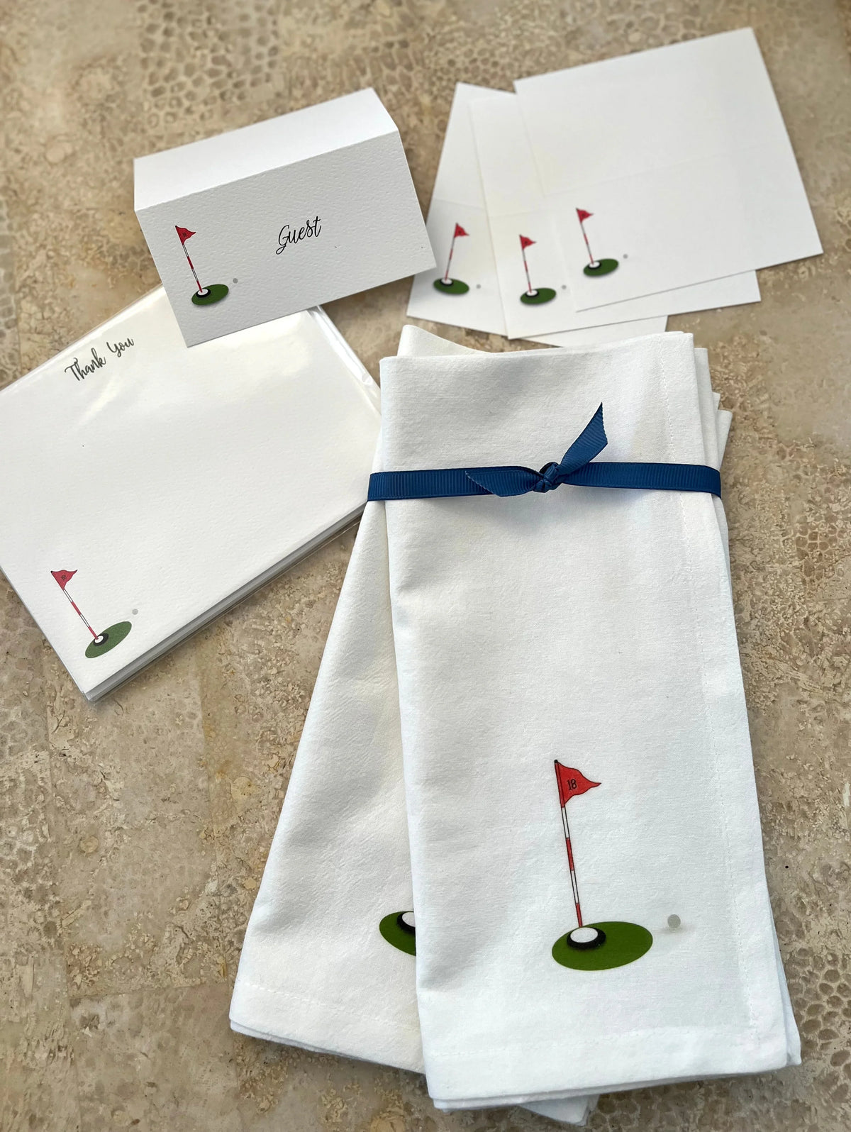 Golf-themed cotton napkins with red flag design, paired with matching place cards and thank you notes for elegant entertaining.