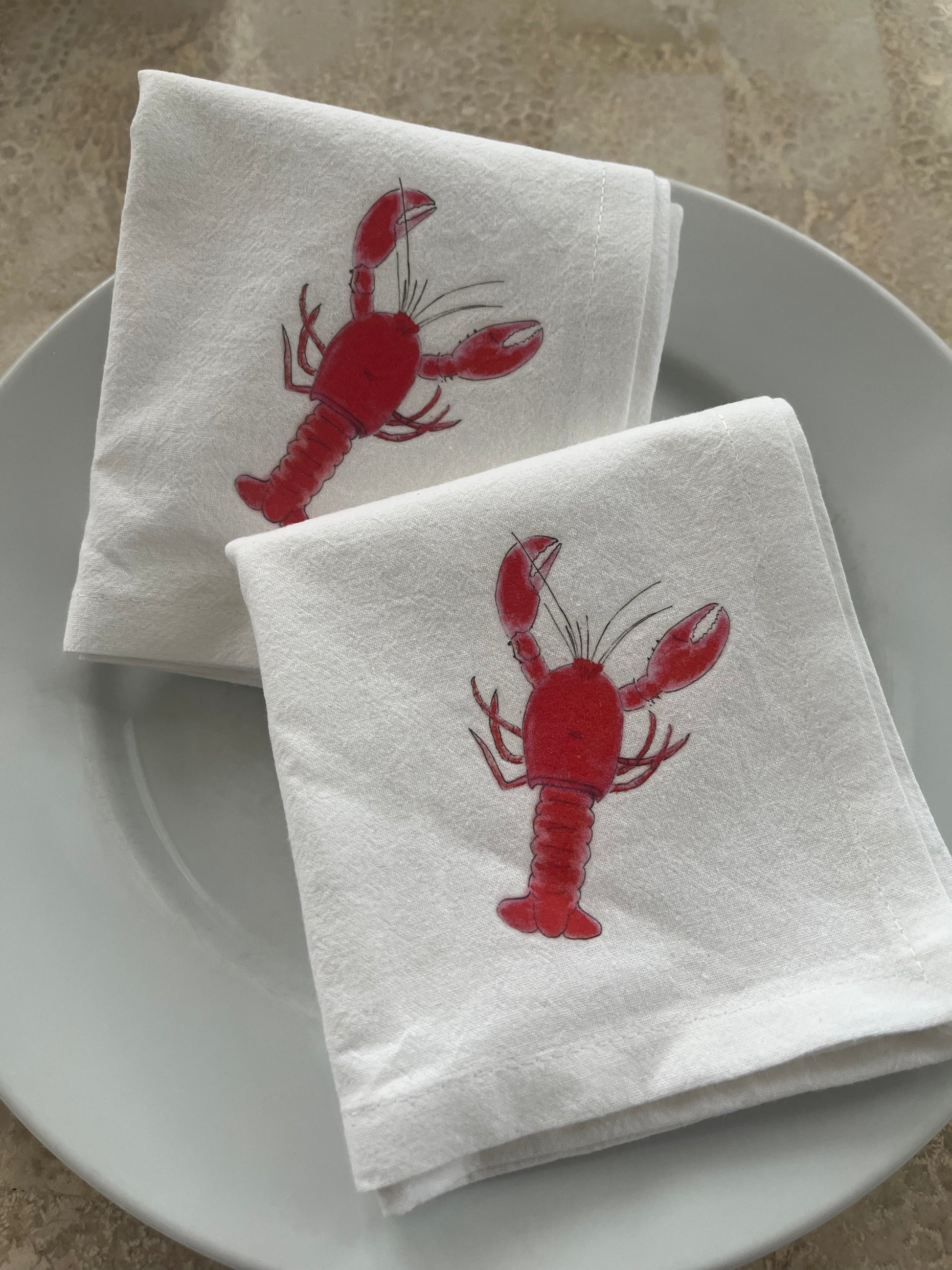 White cotton napkins with red lobster illustration on a white plate
