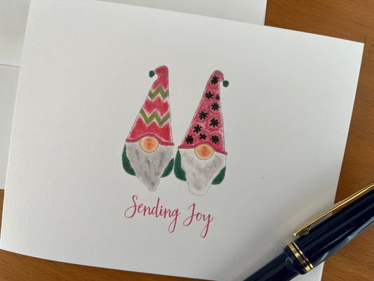 Festive holiday card with two illustrated gnomes in red hats, 'Sending Joy' text, perfect for seasonal greetings.