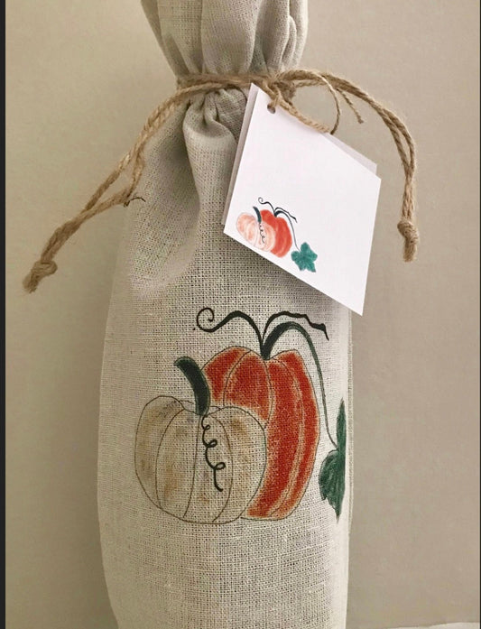 Burlap wine bag with pumpkin design and tag on a neutral background