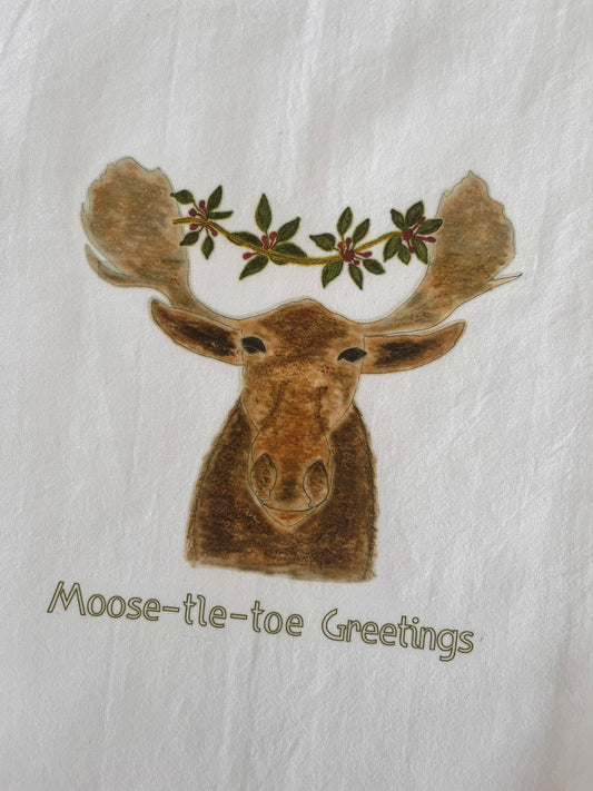 Moose illustration with mistletoe on antlers, 'Moose-tle-toe Greetings' text, nature-inspired tea towel design