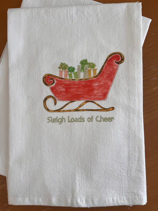 White tea towel with red sleigh design carrying gift boxes, text 'Sleigh Loads of Cheer', perfect for holiday gatherings.