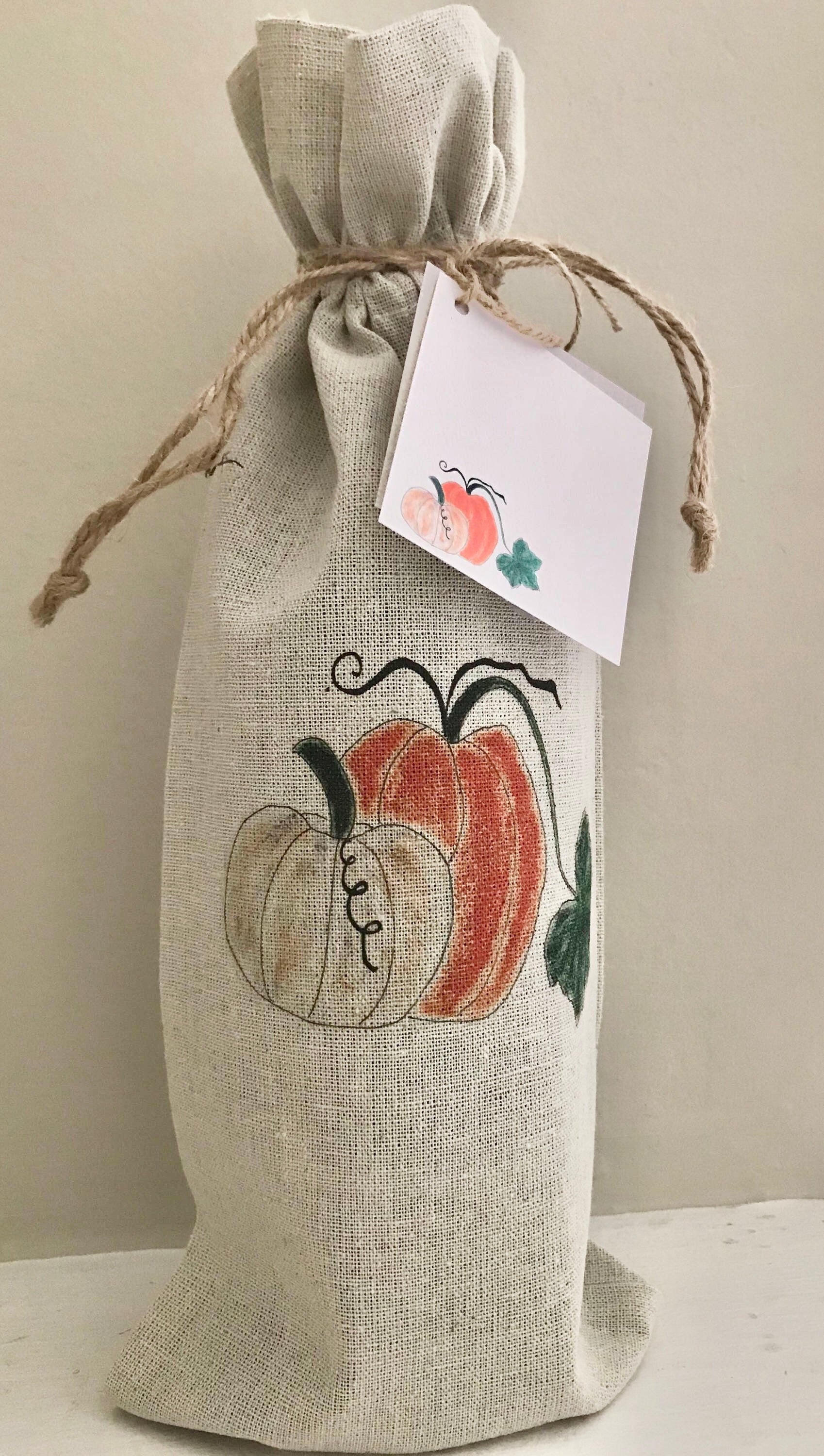 Burlap wine bag with pumpkins and a tag on a neutral background