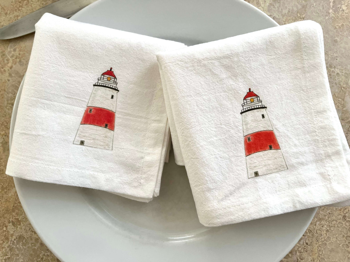 Lighthouse Napkin Set displayed on a plate featuring hand-illustrated lighthouse artwork for coastal dining elegance.