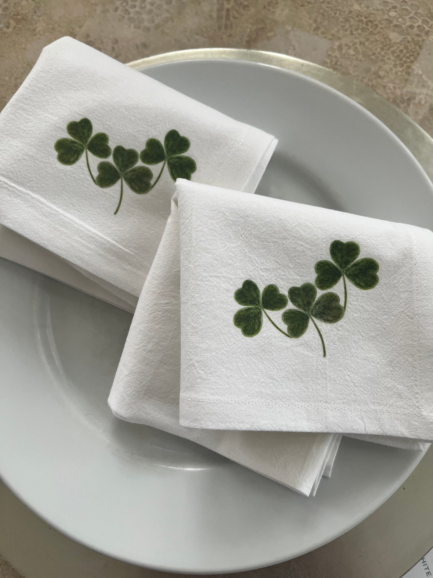 Shamrock Cotton Napkin Set on a white plate, featuring hand-illustrated shamrock designs for festive dining.