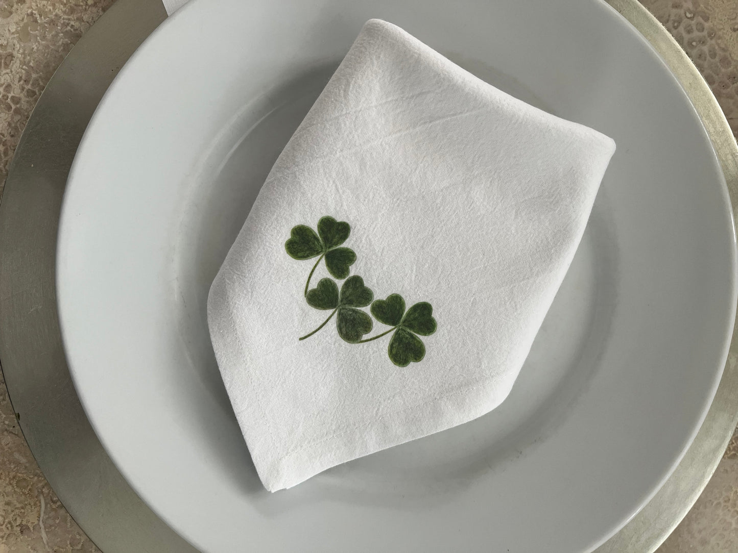 Shamrock Cotton Napkin Set displayed on a plate, featuring hand-illustrated shamrock design for festive dining.