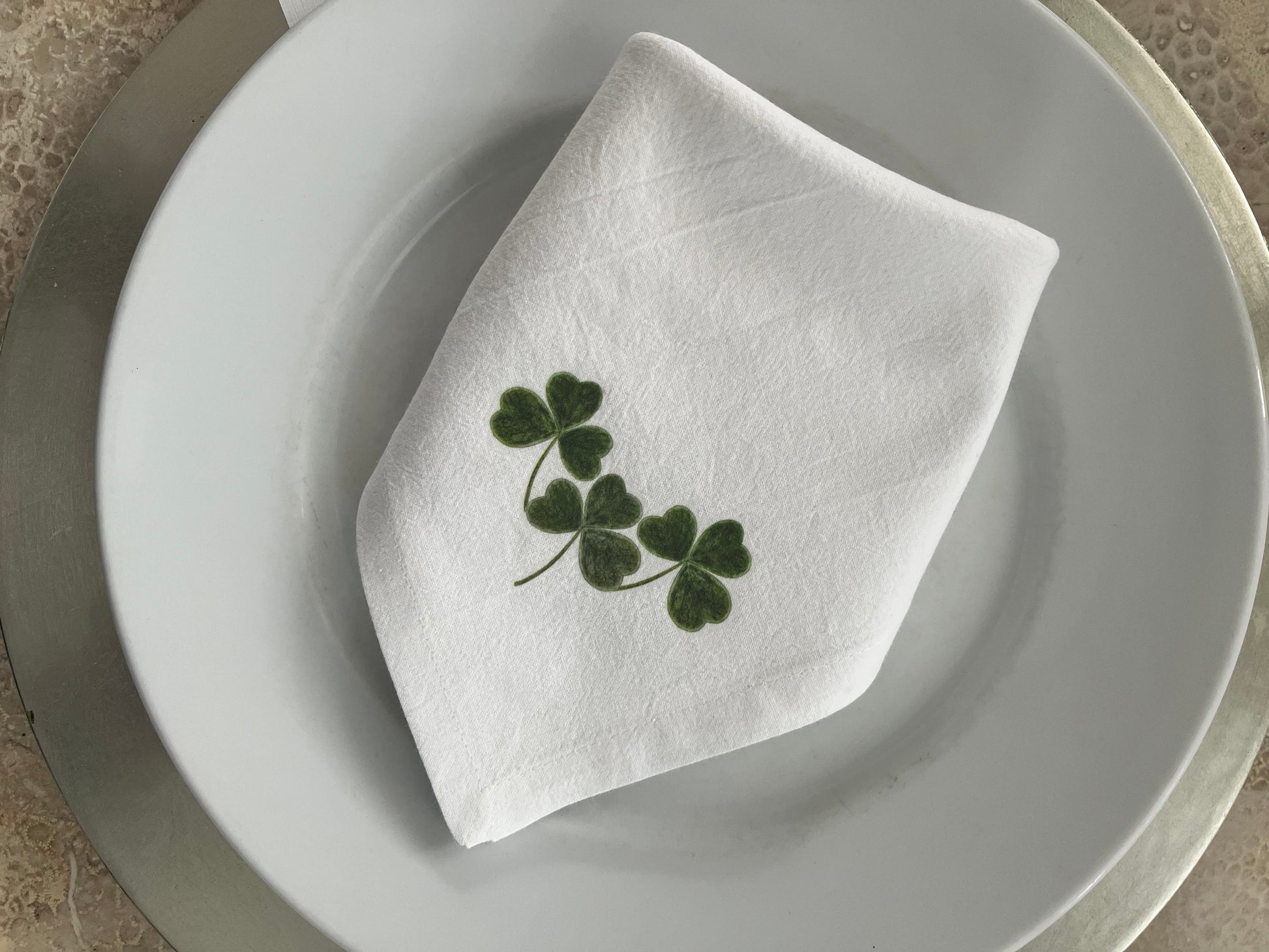 Shamrock Cotton Napkin Set displayed on a plate, featuring hand-illustrated shamrock design for festive dining.