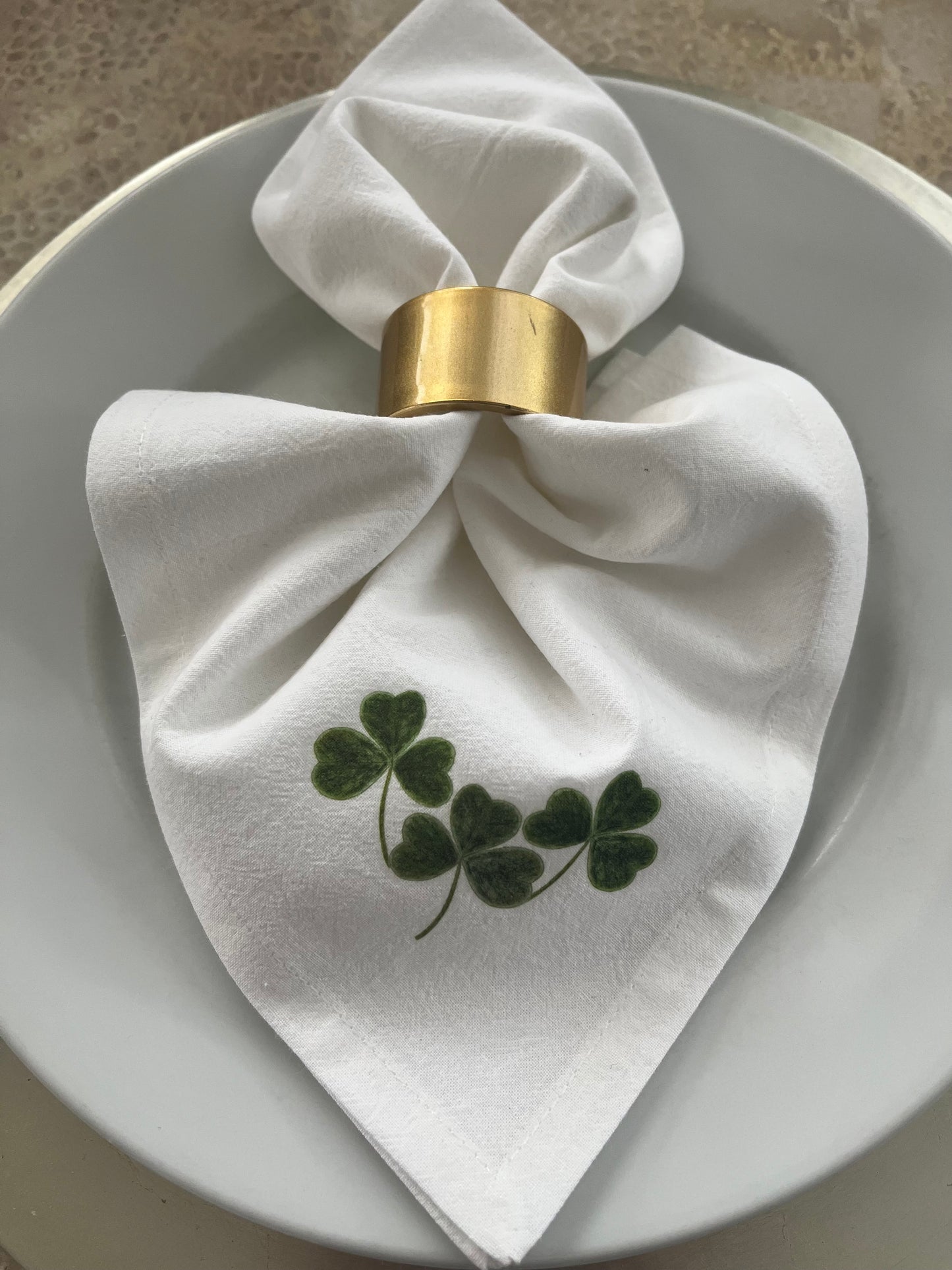 Shamrock Cotton Napkin Set elegantly arranged on a plate, featuring hand-illustrated shamrock design.
