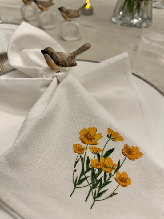 White cotton napkin with yellow wildflower print, styled with ceramic bird napkin ring for elegant table setting
