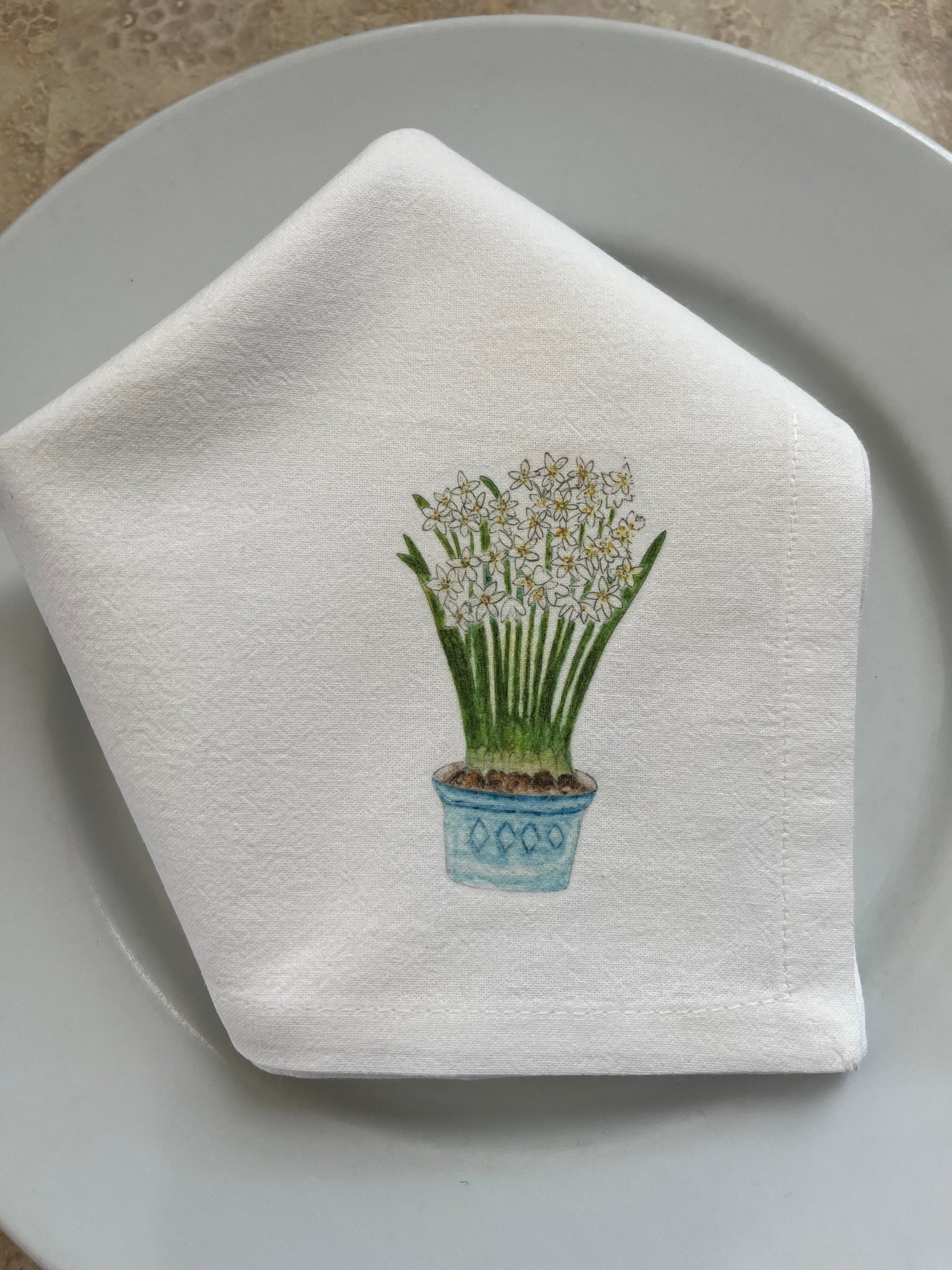 Cotton napkin with illustrated potted white flowers on a white plate, nature-inspired design