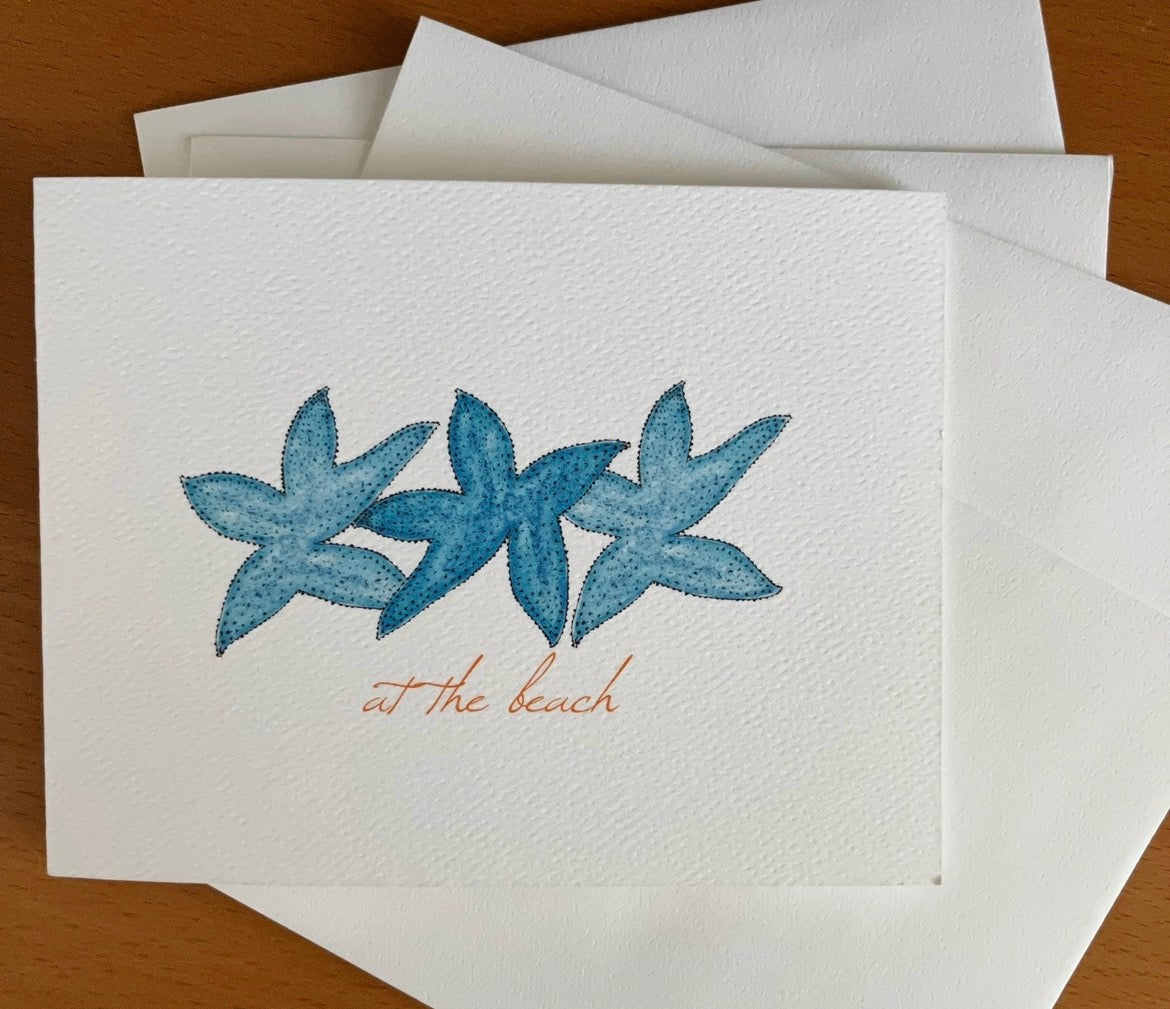 Illustrated note card with blue starfish and 'at the beach' text, on textured paper