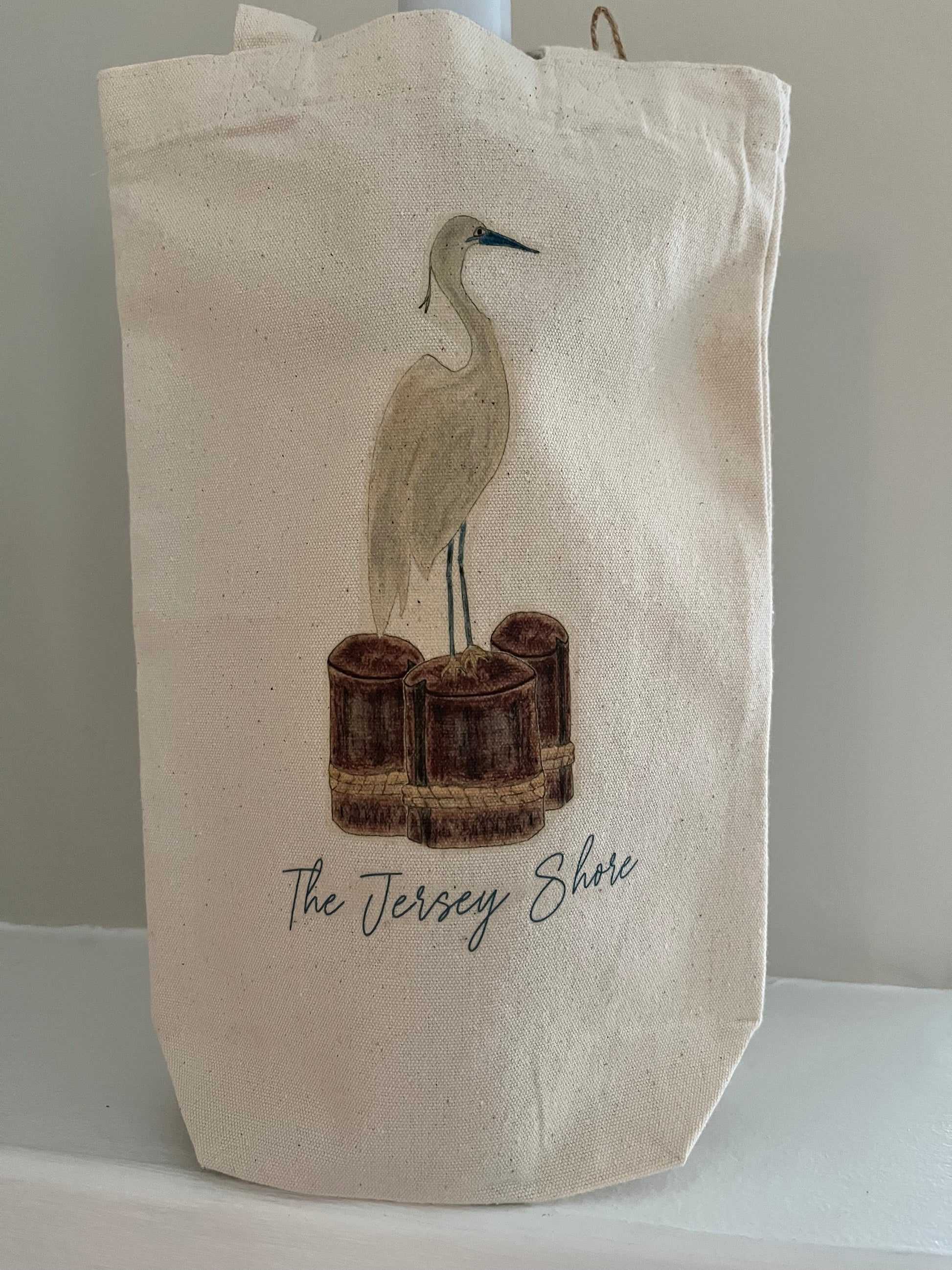 Canvas tote bag with illustrated shorebird, wooden pilings, and text 'The Jersey Shore'.
