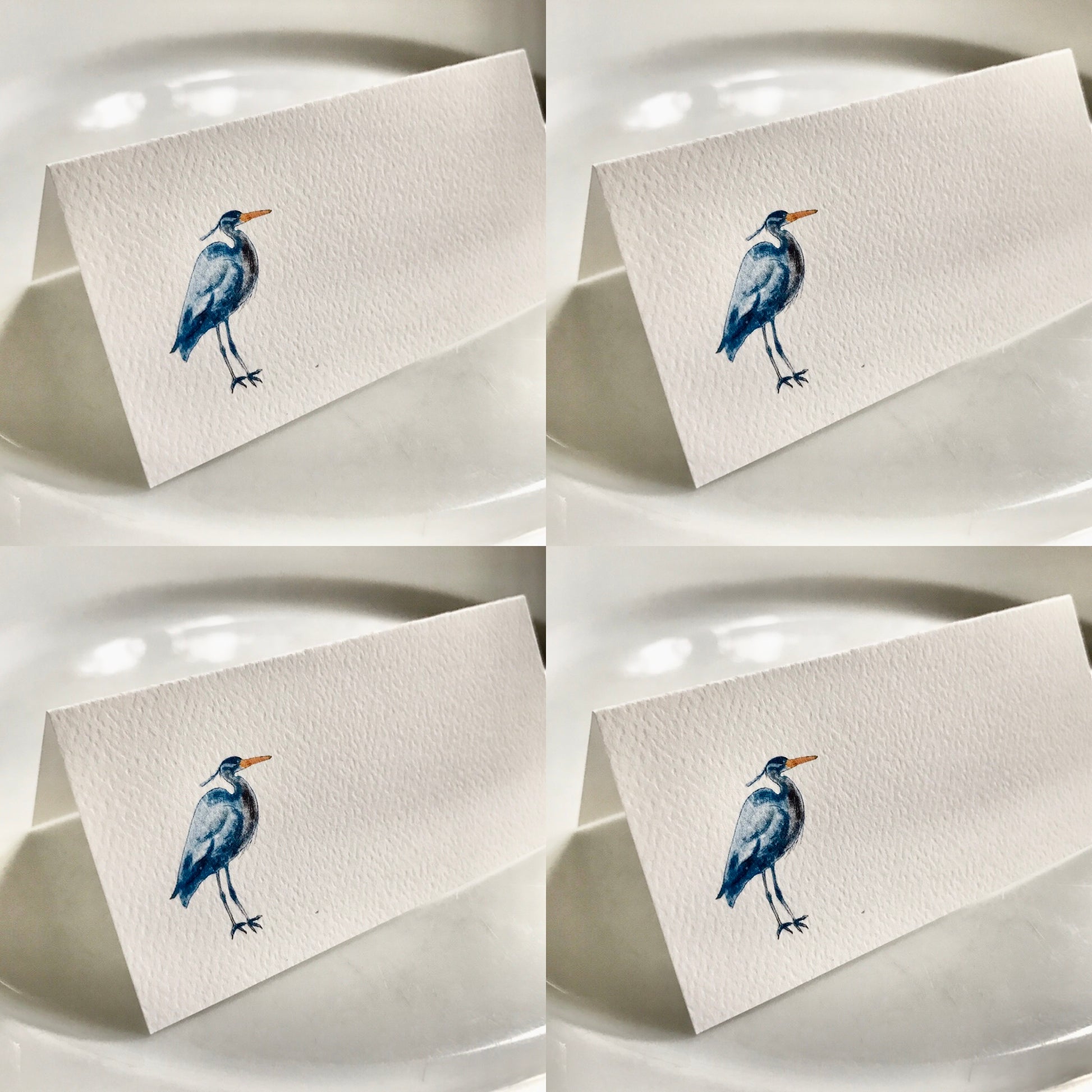 Watercolor heron illustrated tented place card on white plate, nature-inspired table decor.